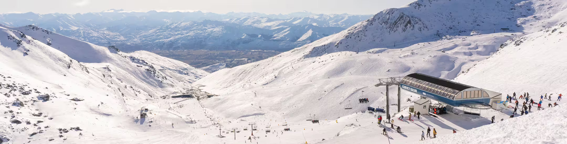 Snowy mountain landscape with ski lift and people at a ski resort.