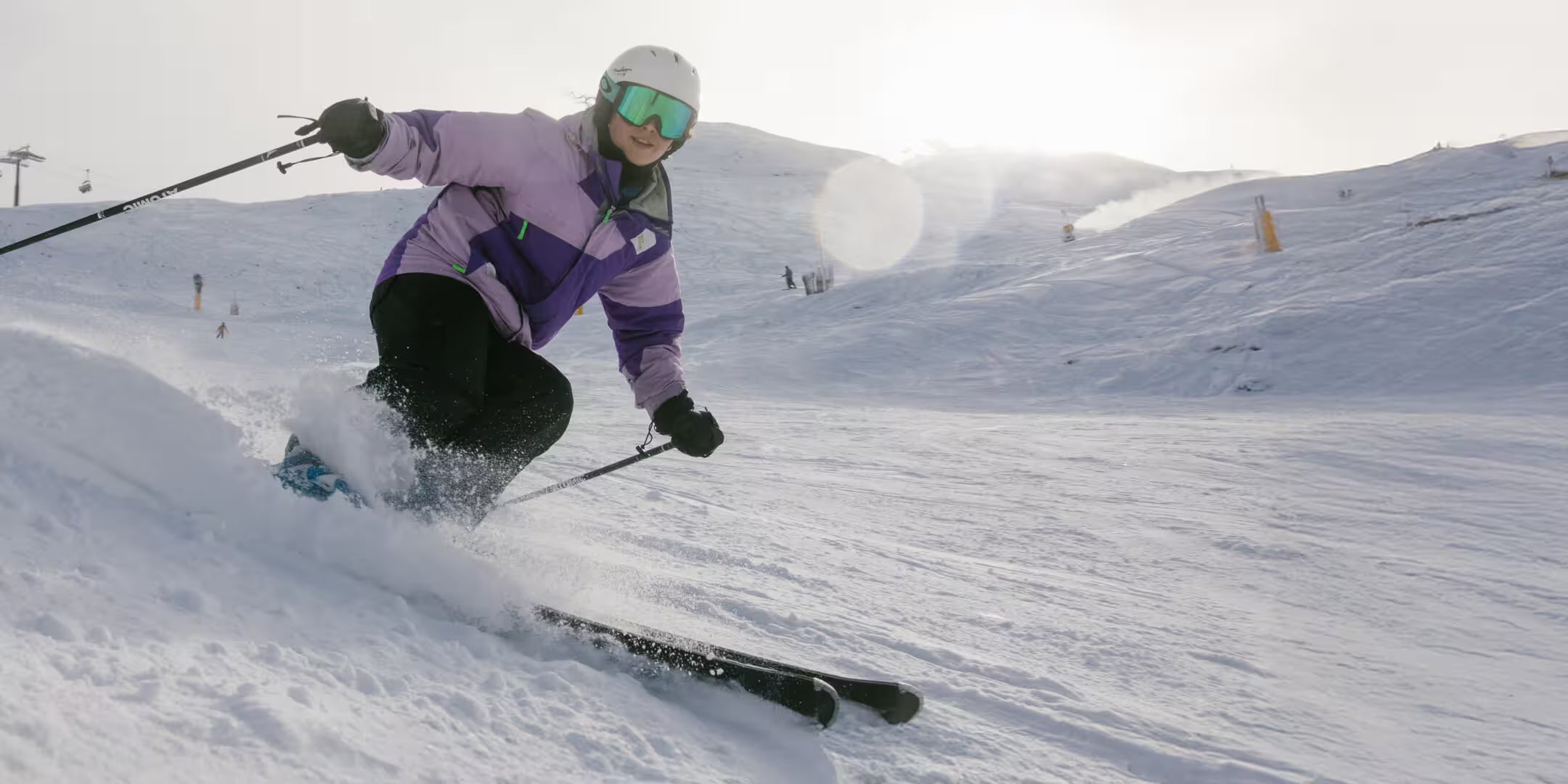 Person skiing down a snowy slope with a helmet and goggles on