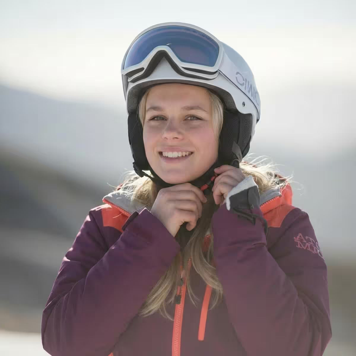 Person wearing a helmet and ski jacket with a blurred background