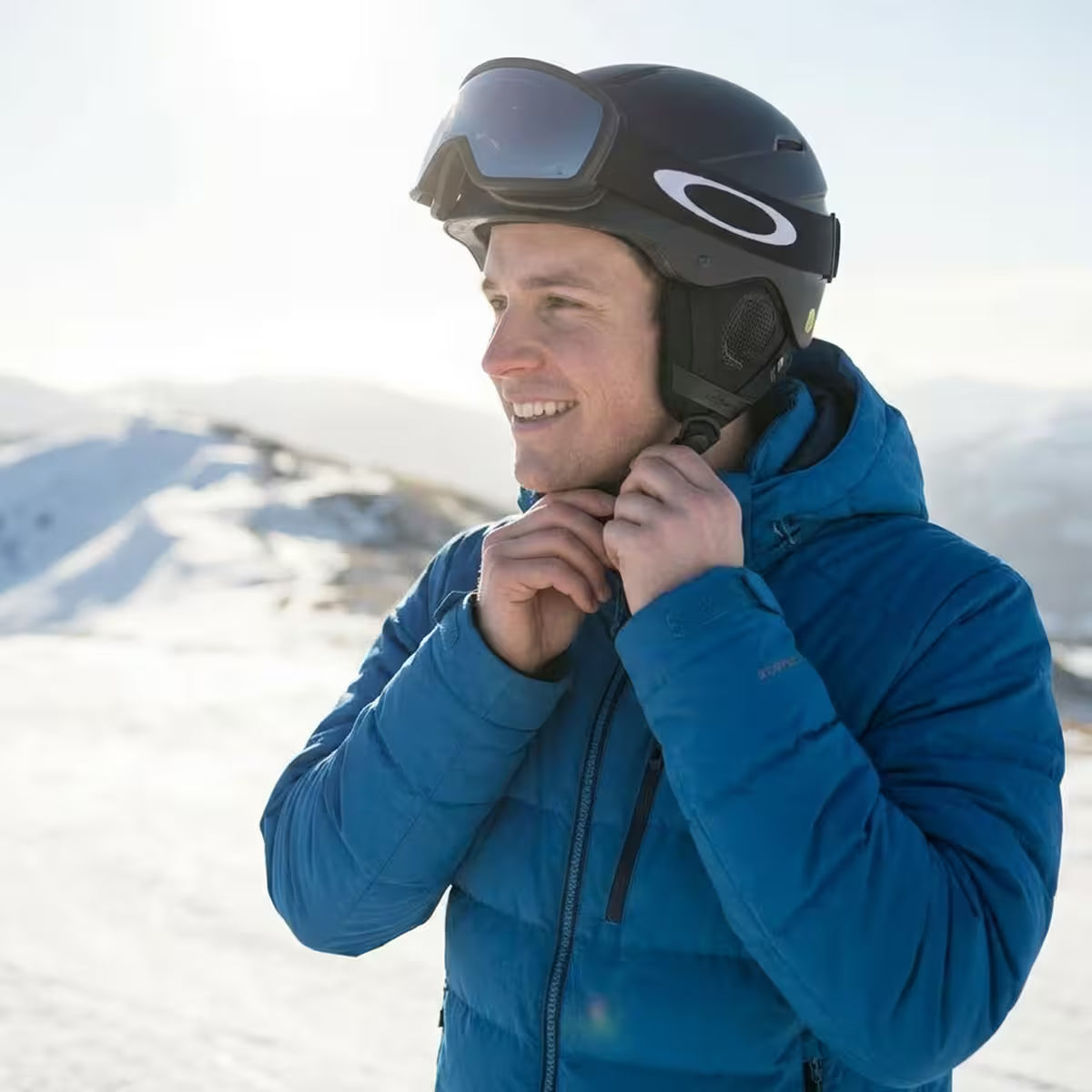 Man in blue jacket and black helmet with goggles on a snowy background