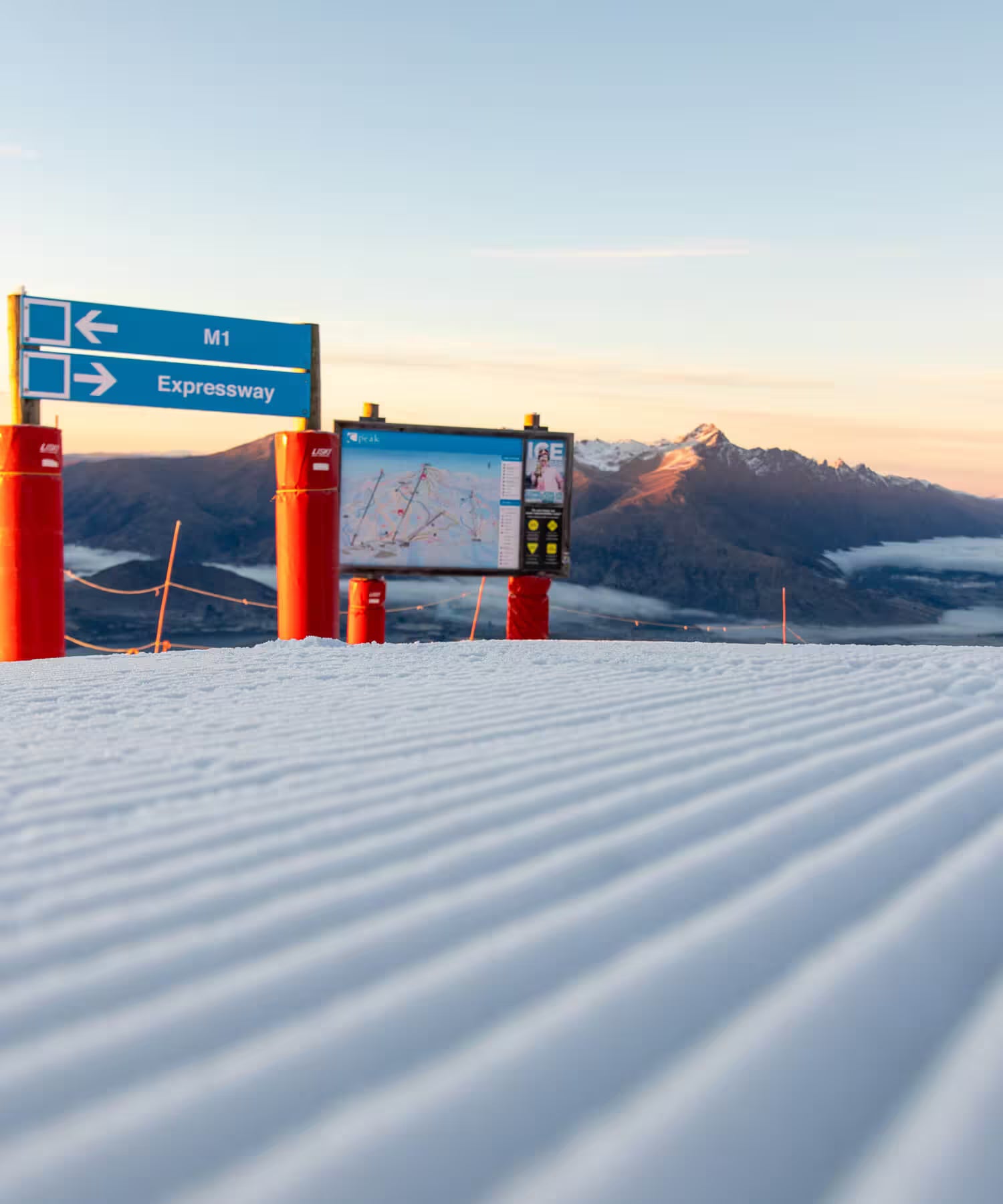 Snowy landscape with road signs and digital display against a mountainous background