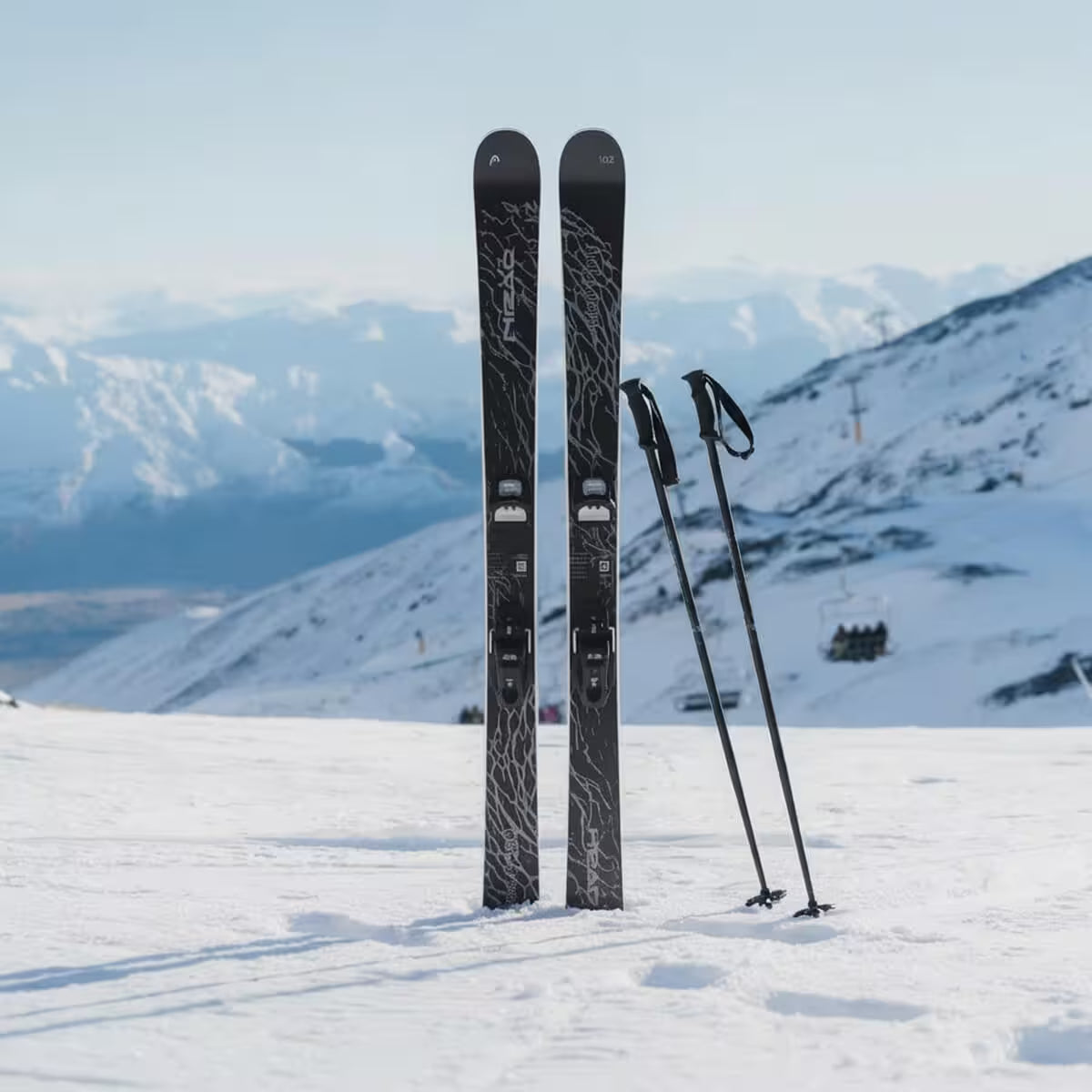 Two skis and ski poles on a snowy mountain with a scenic background